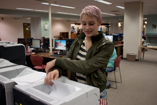 Amy Asanuma | Argonaut Junior Emily Forsberg sifts through paper in search of an essay at the campus library. ITS and the Sustainability Center worked to establish default front-back printing campus-wide.